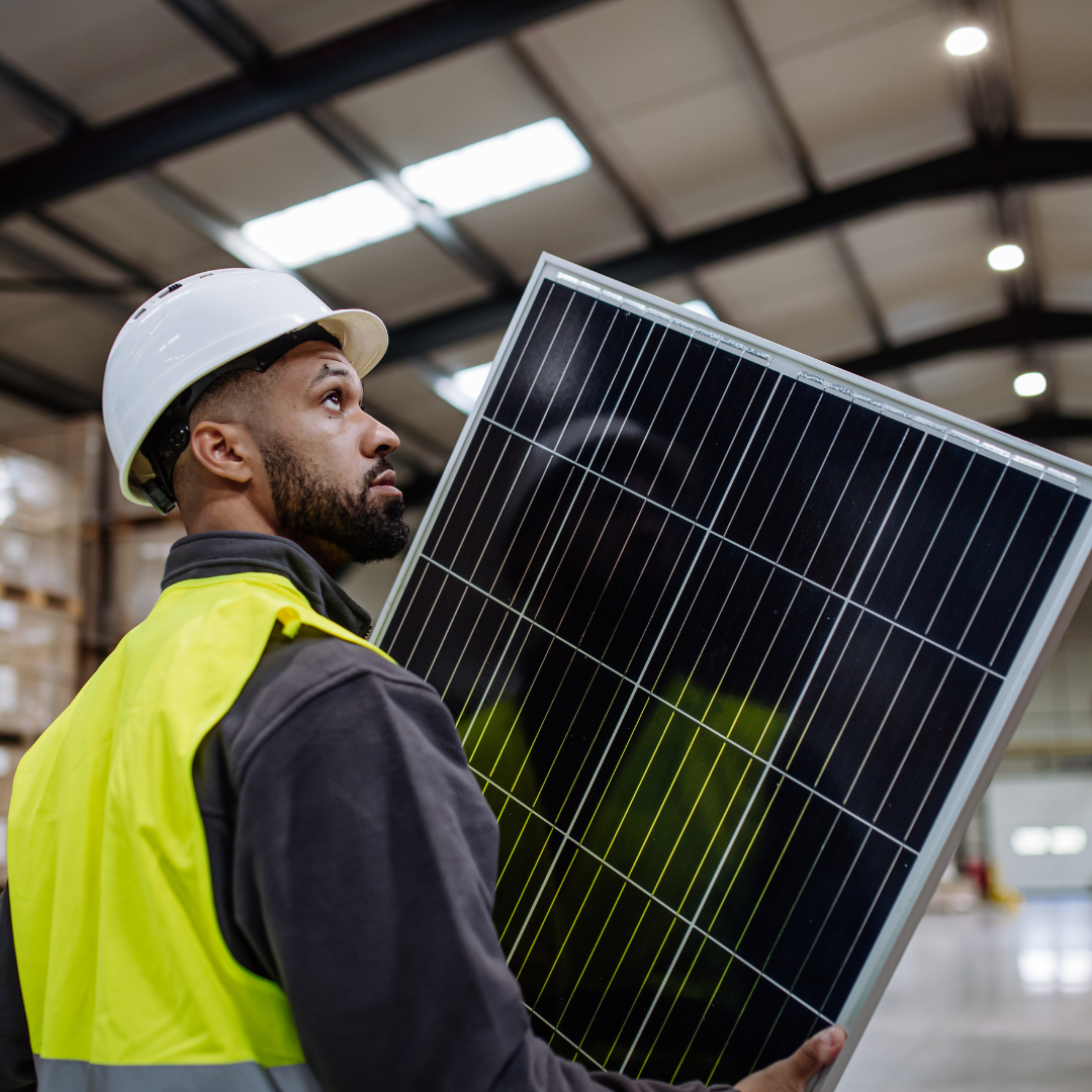 Installer with a hard hat and reflector jacket carrying a solar panel | Daisy